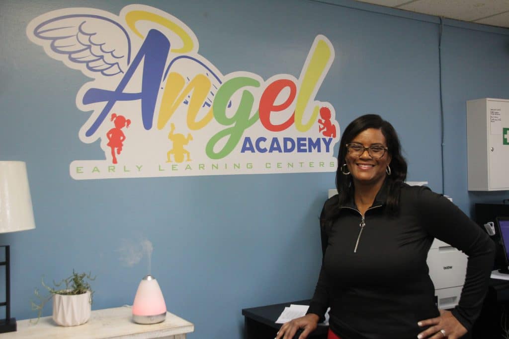 IMG_5047 Tracy Smith stands in front of her Angel Academy Early Learning Centers Logo