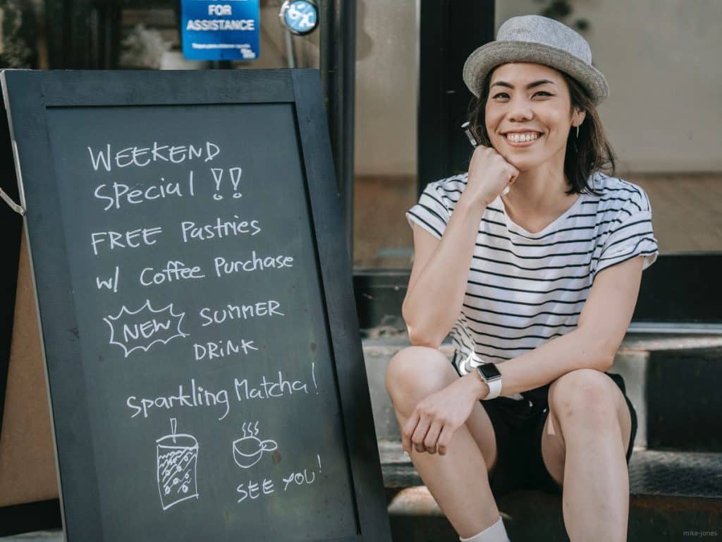 Effective-Pricing-Strategy-for-Small-Business-TEDC-1200x900 Person sitting next to a chalkboard sign with special pricing listed