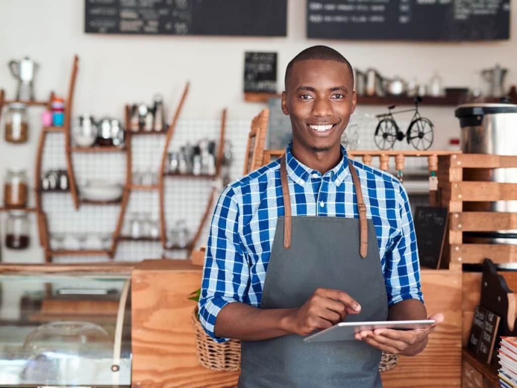 Solving-Cash-Flow-Problems-and-Growth-Small-Businesses-TEDC-1200x900 Small business owner smiling and holding a tablet